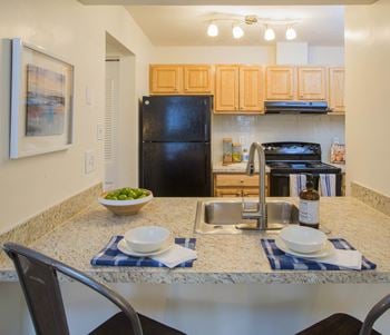 A kitchen with a black refrigerator freezer next to a stove top oven